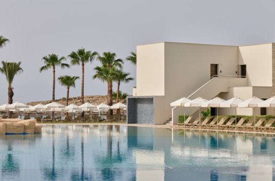 a pool with white umbrellas and a building by it