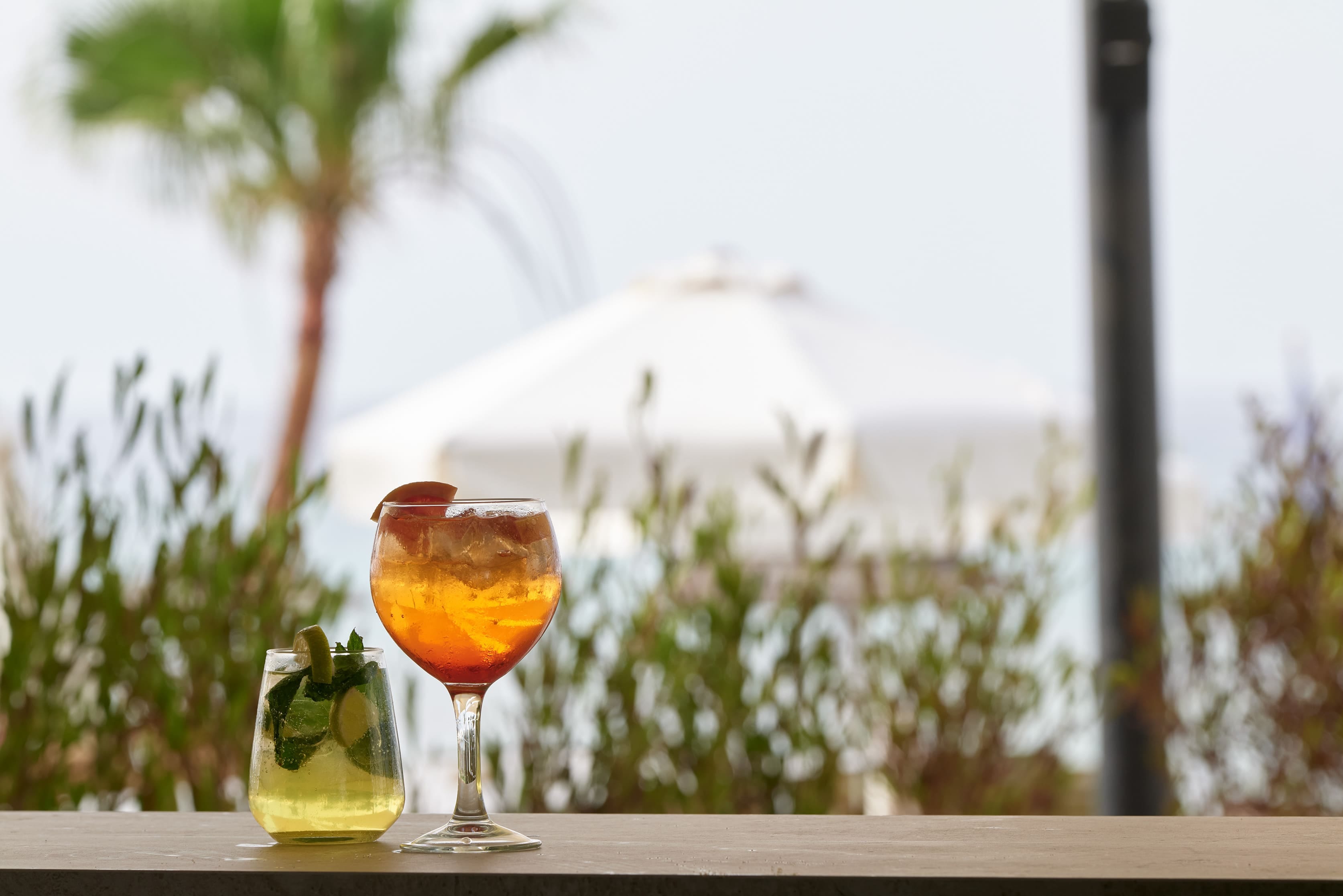 a glass of liquid and a bottle of lemon on a table