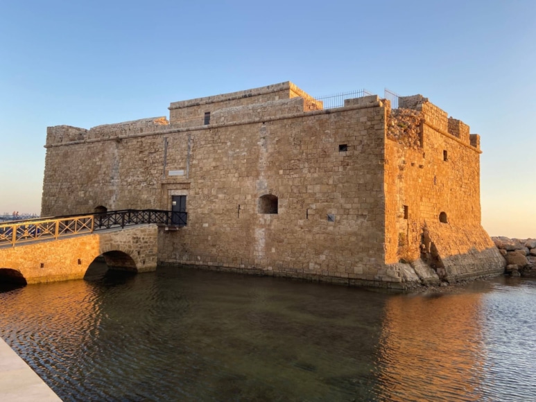 a stone castle on a hill over water with Paphos Castle in the background