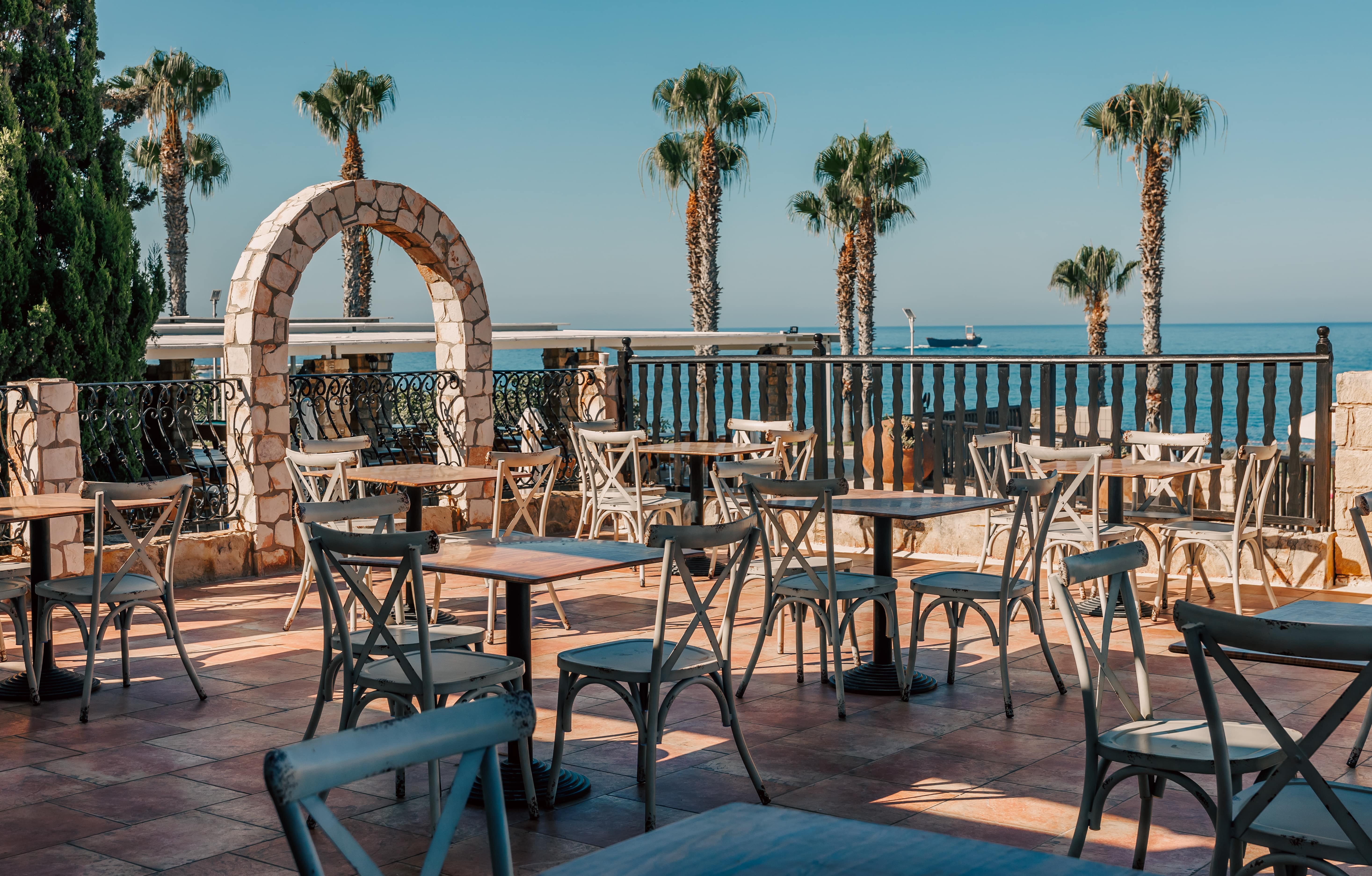 a patio with tables and chairs by the water