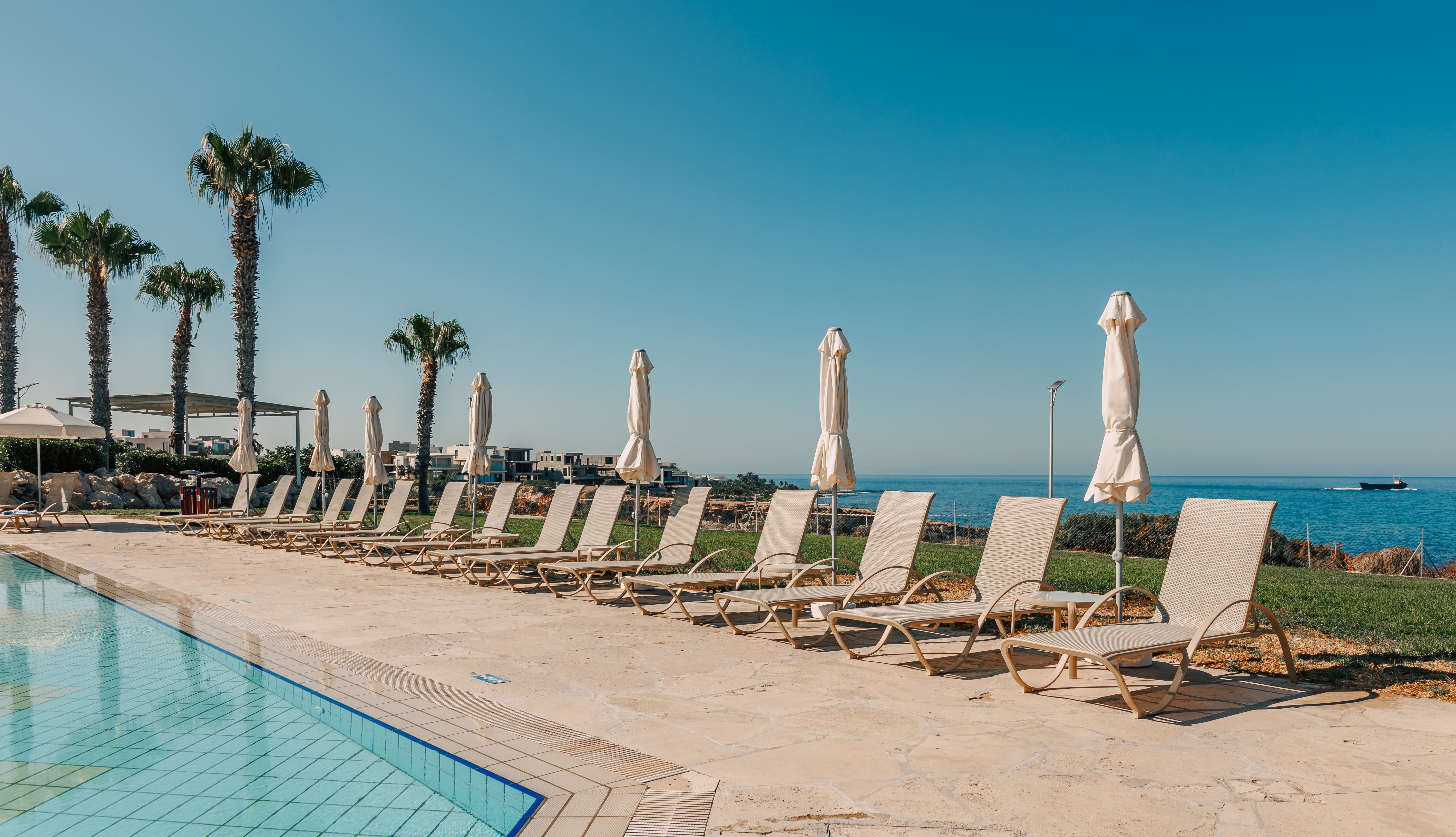 a pool with chairs and umbrellas by a beach
