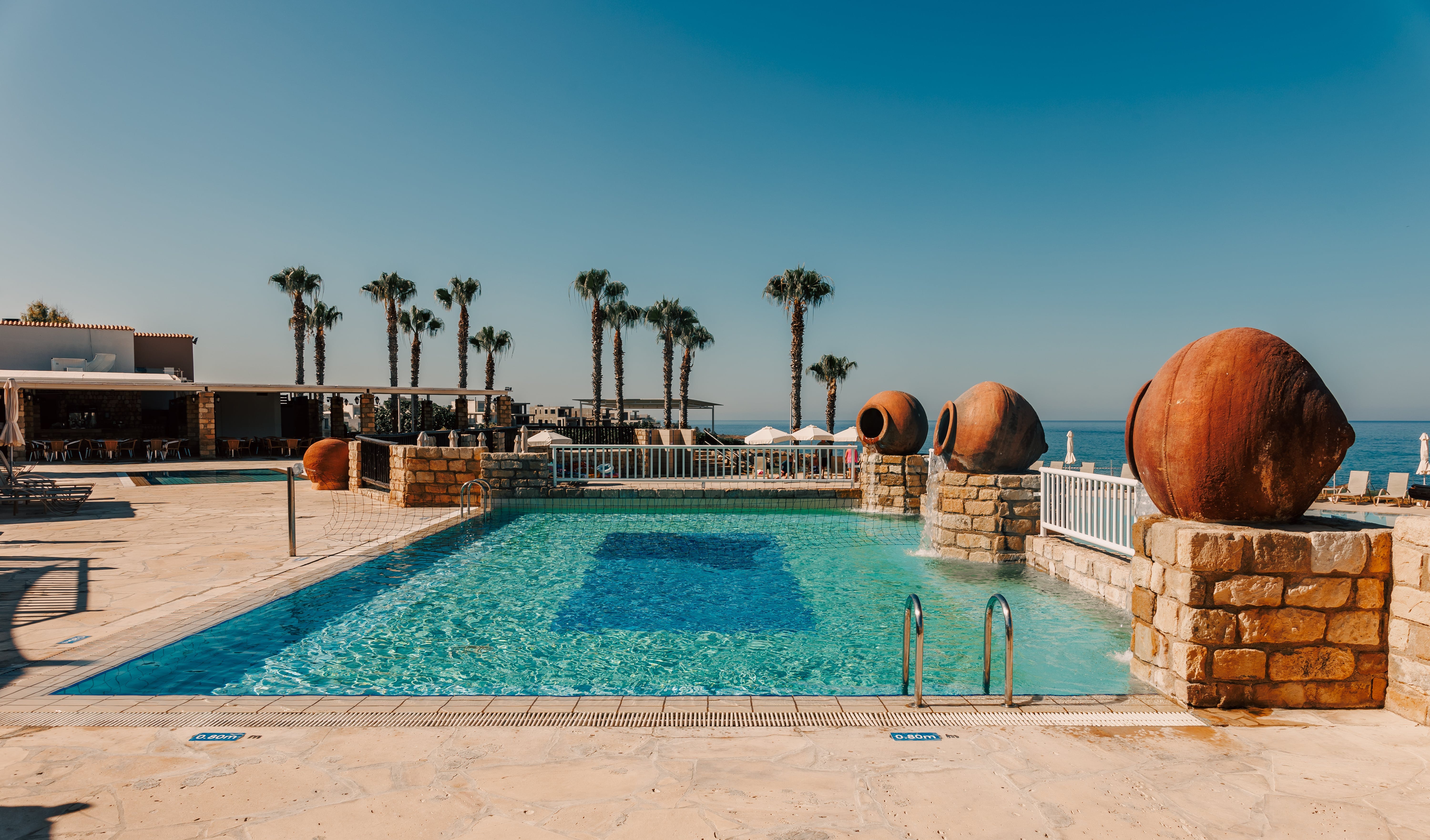 a pool with a stone wall and palm trees in the background