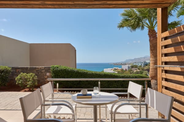 a deck with a table and chairs and a body of water in the background