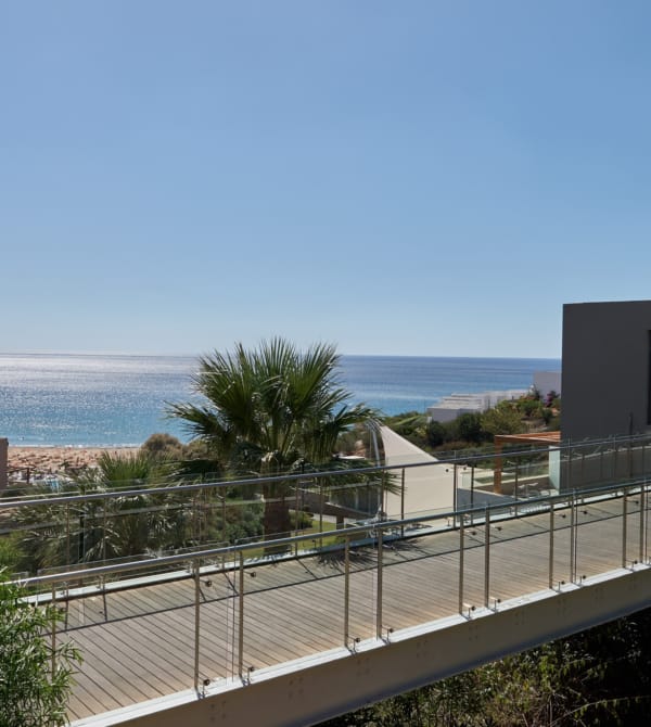 a building with a fence and trees by the ocean