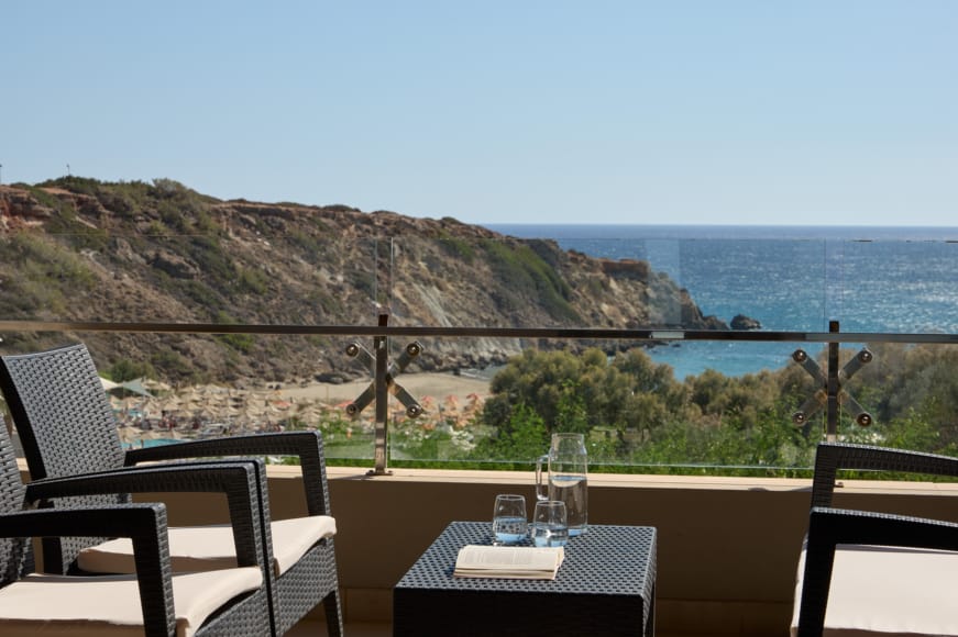 a table and chairs on a balcony overlooking a body of water