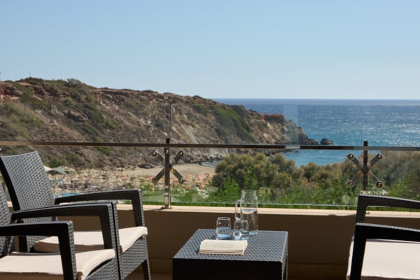 a table and chairs on a balcony overlooking a body of water
