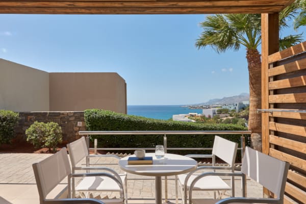 a deck with a table and chairs and a body of water in the background