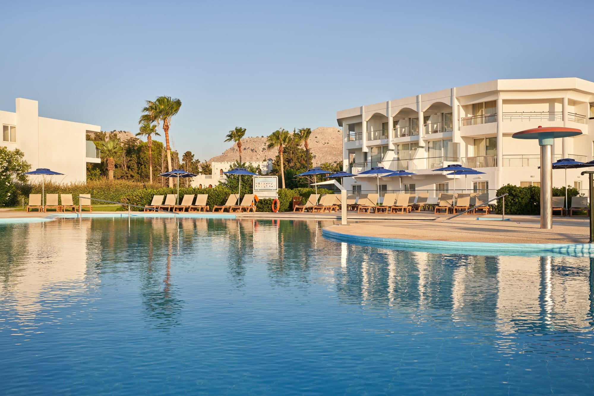 a pool with umbrellas by a building