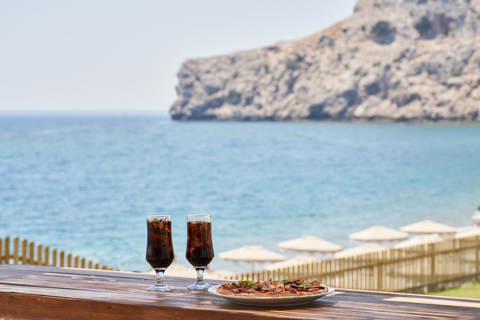 a couple of glasses of wine on a deck overlooking a body of water