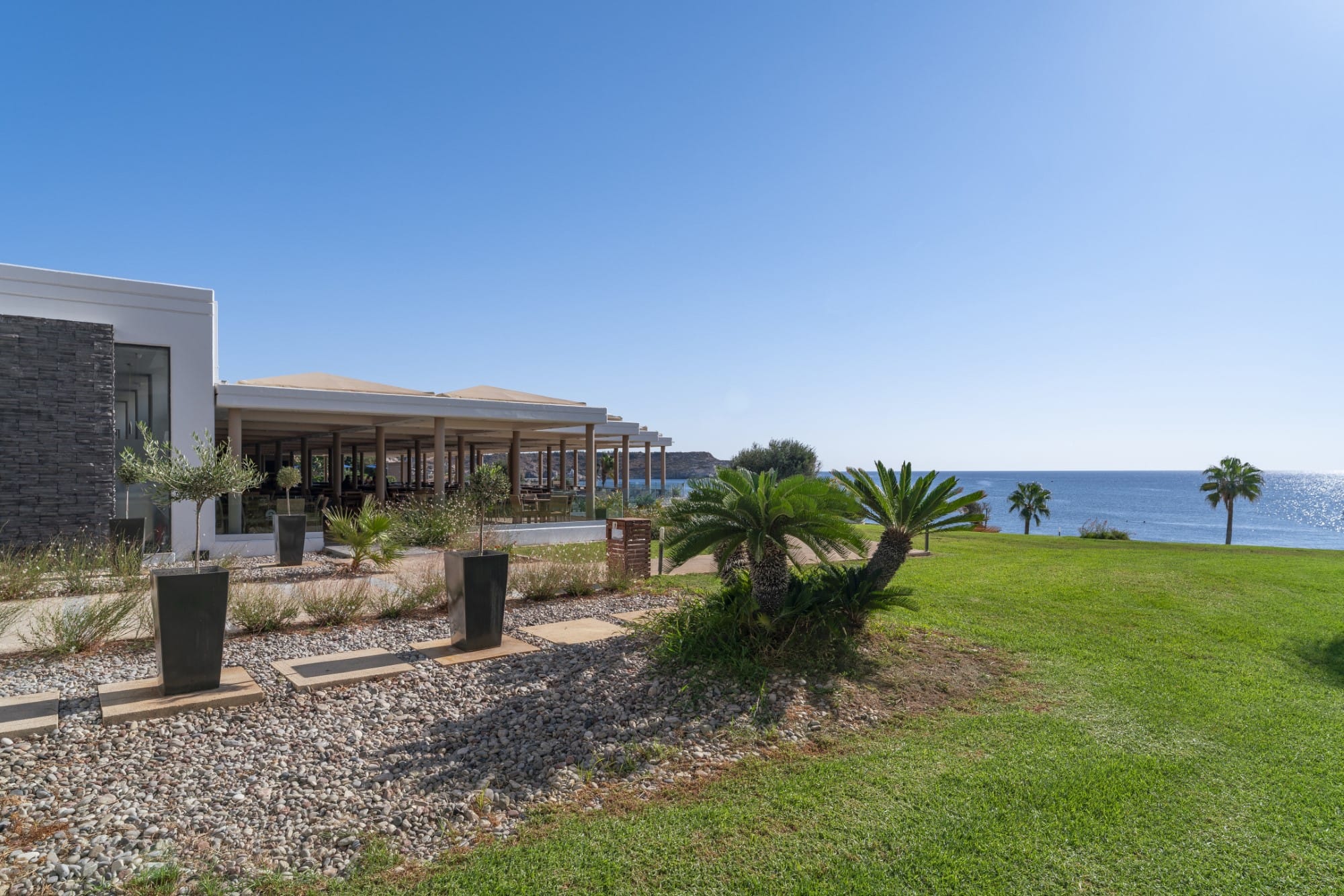 a building with a grass yard and trees by the water