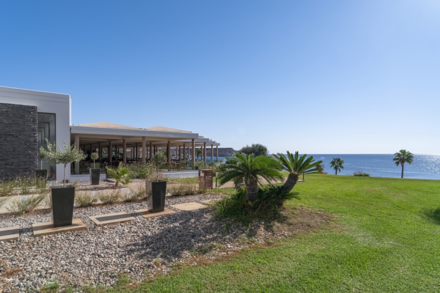 a building with a grass yard and trees by the water