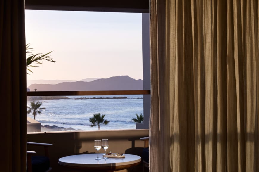 a table and chairs in front of a window with a view of the ocean