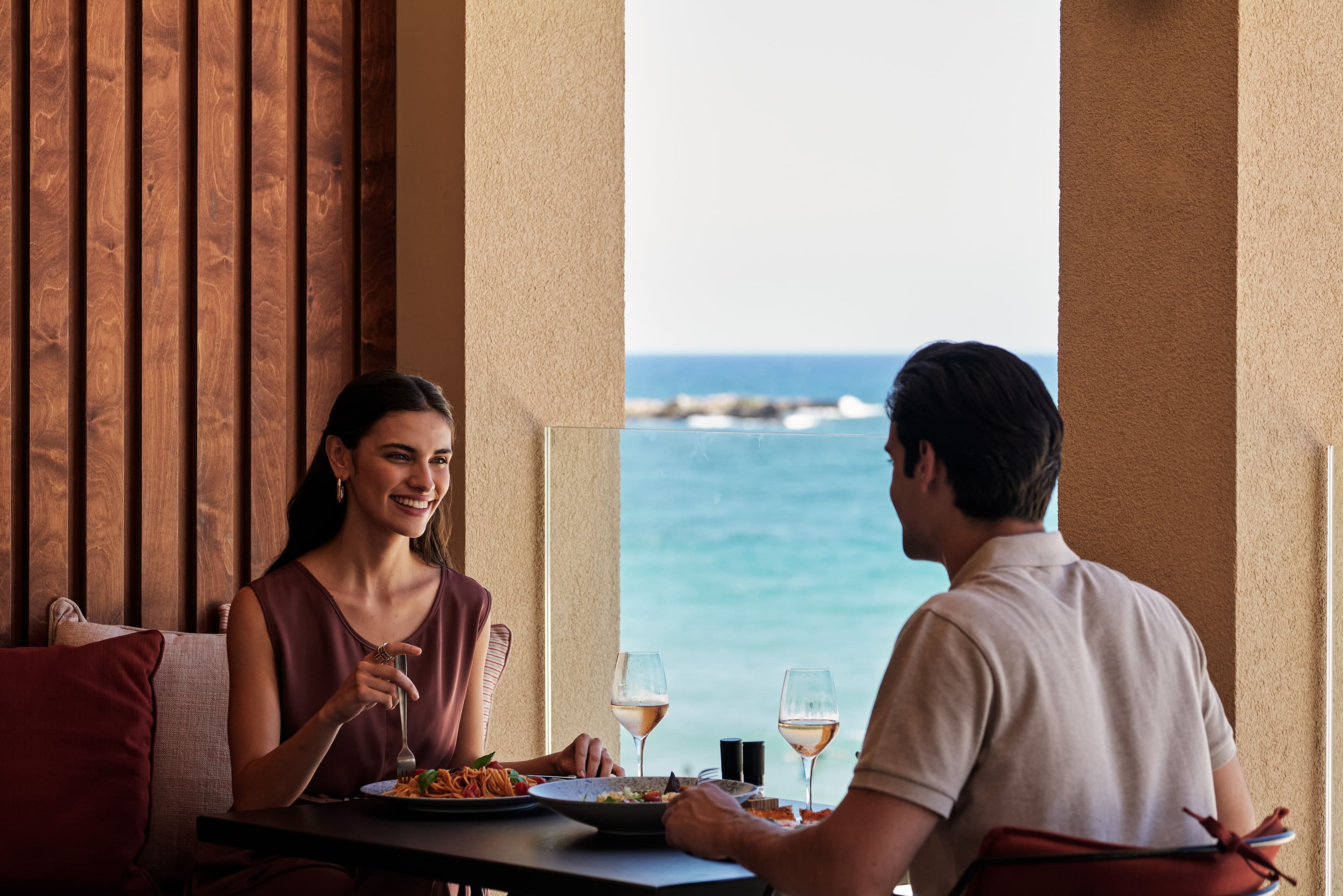 a man and a woman sitting at a table with food and drinks