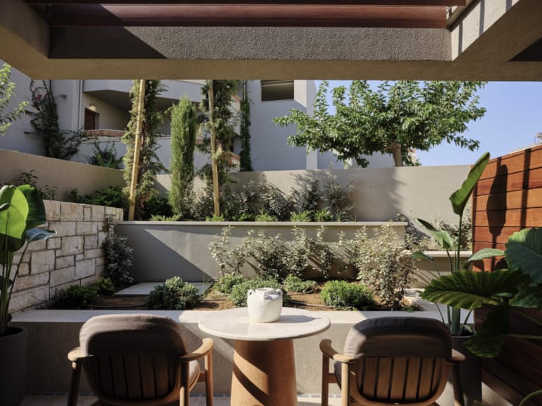 a table and chairs in a room with plants and a stone wall