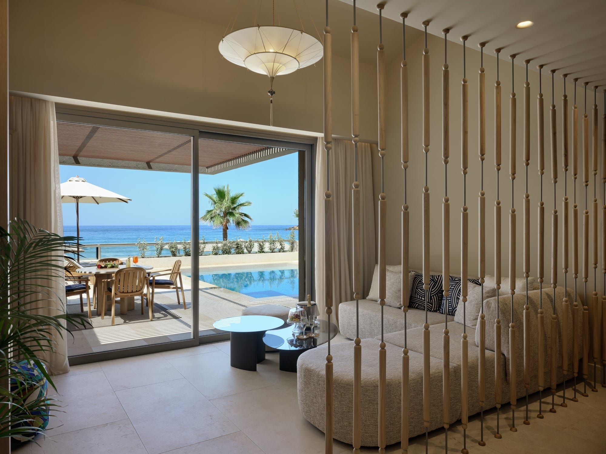 a room with a couch and a table and chairs and a view of the ocean