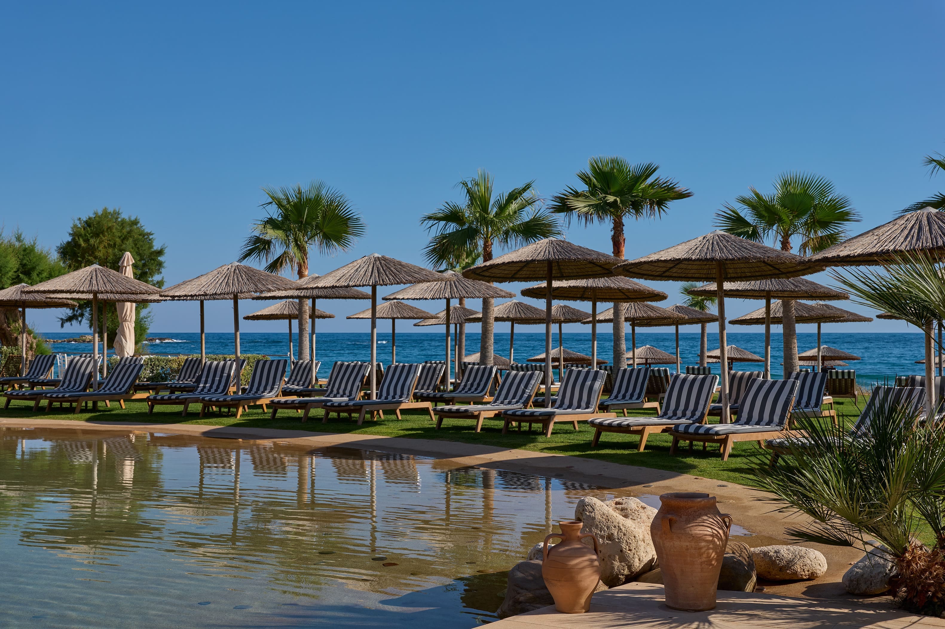 a body of water with umbrellas and chairs by it