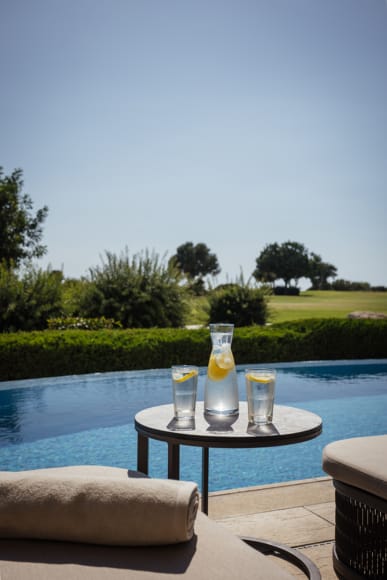 a table with glasses of liquid on it by a pool