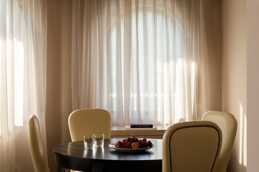 a table with a plate of fruit on it and a chair in the back