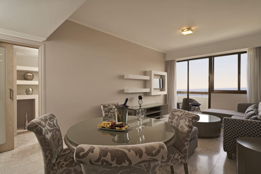 a living room with a glass coffee table and chairs