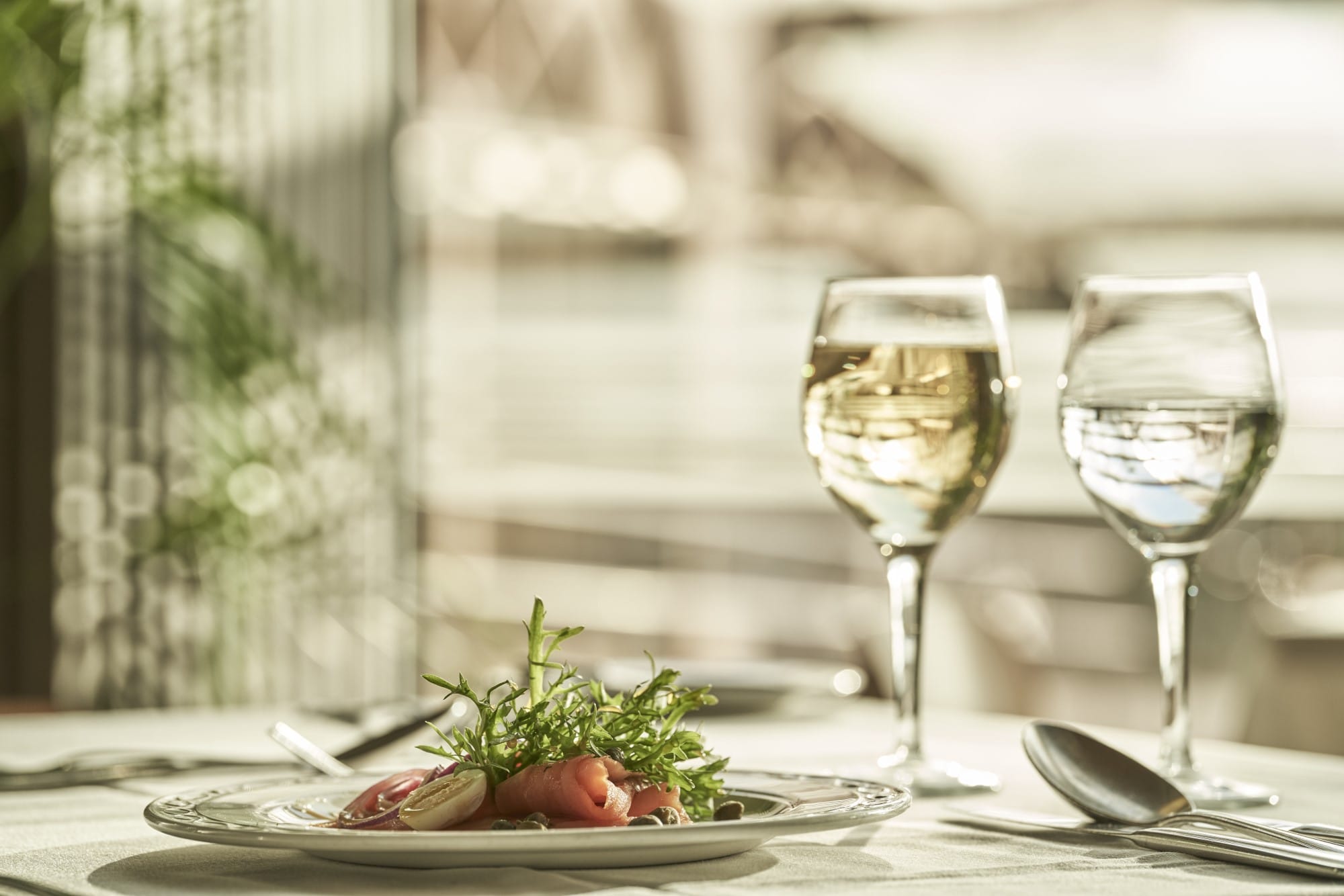 Elegant Dining Setup With Wine Glasses And Gourmet Dish At Atlantica Oasis Hotel In Limassol