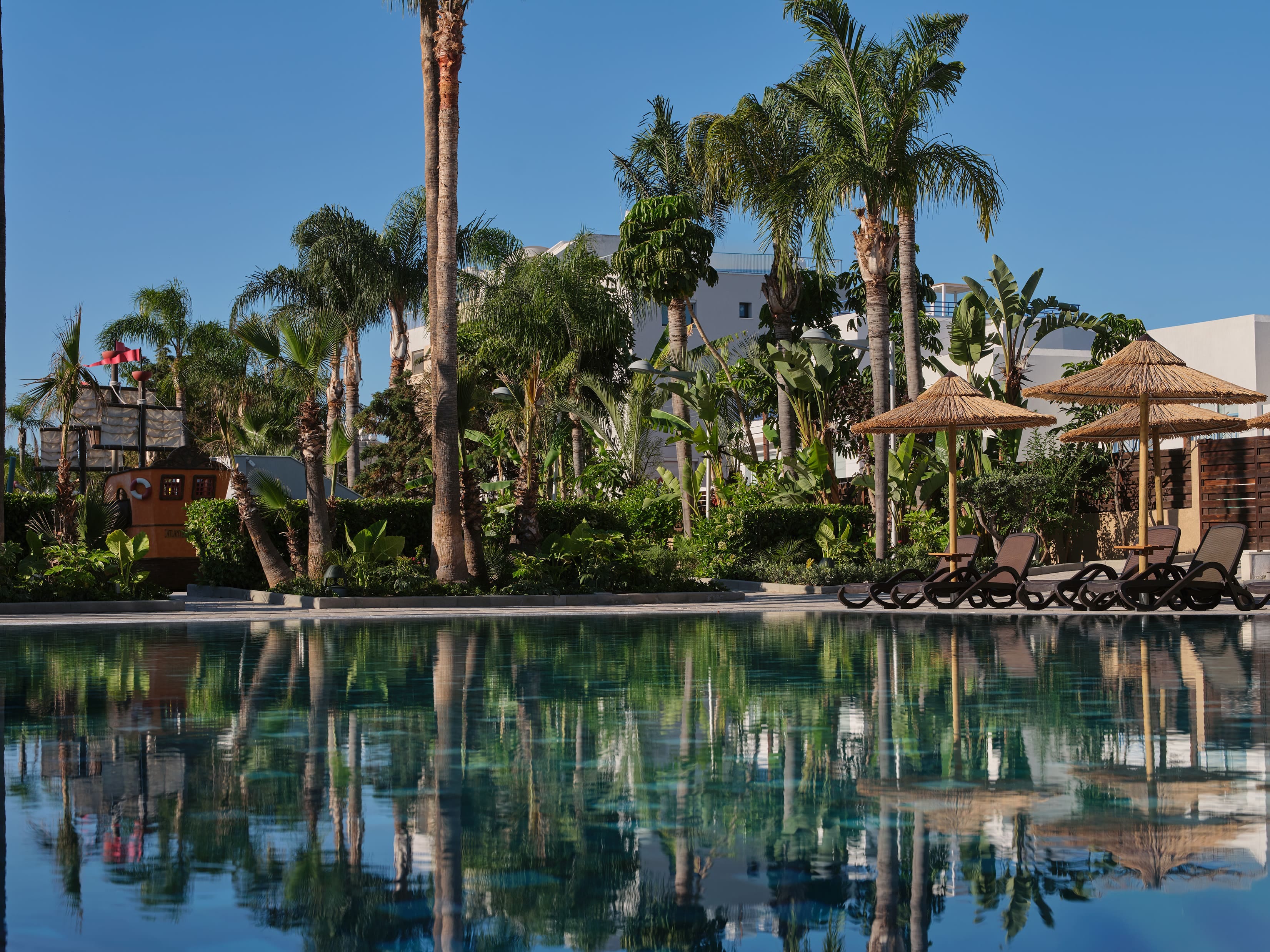 Outdoor Swimming Pool Surrounded By Palm Trees At The Atlantica Oasis Hotel In Limassol, Cyprus