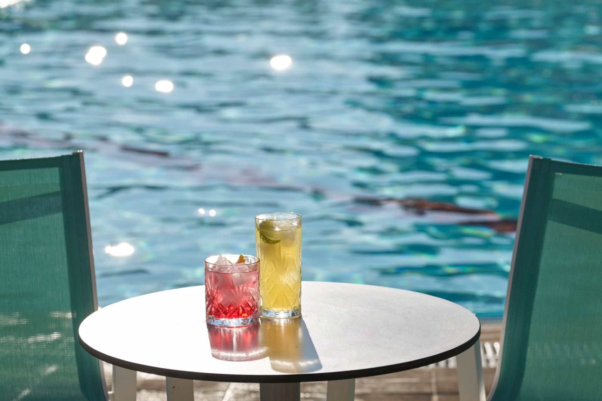 a table with a glass of liquid on it by a body of water