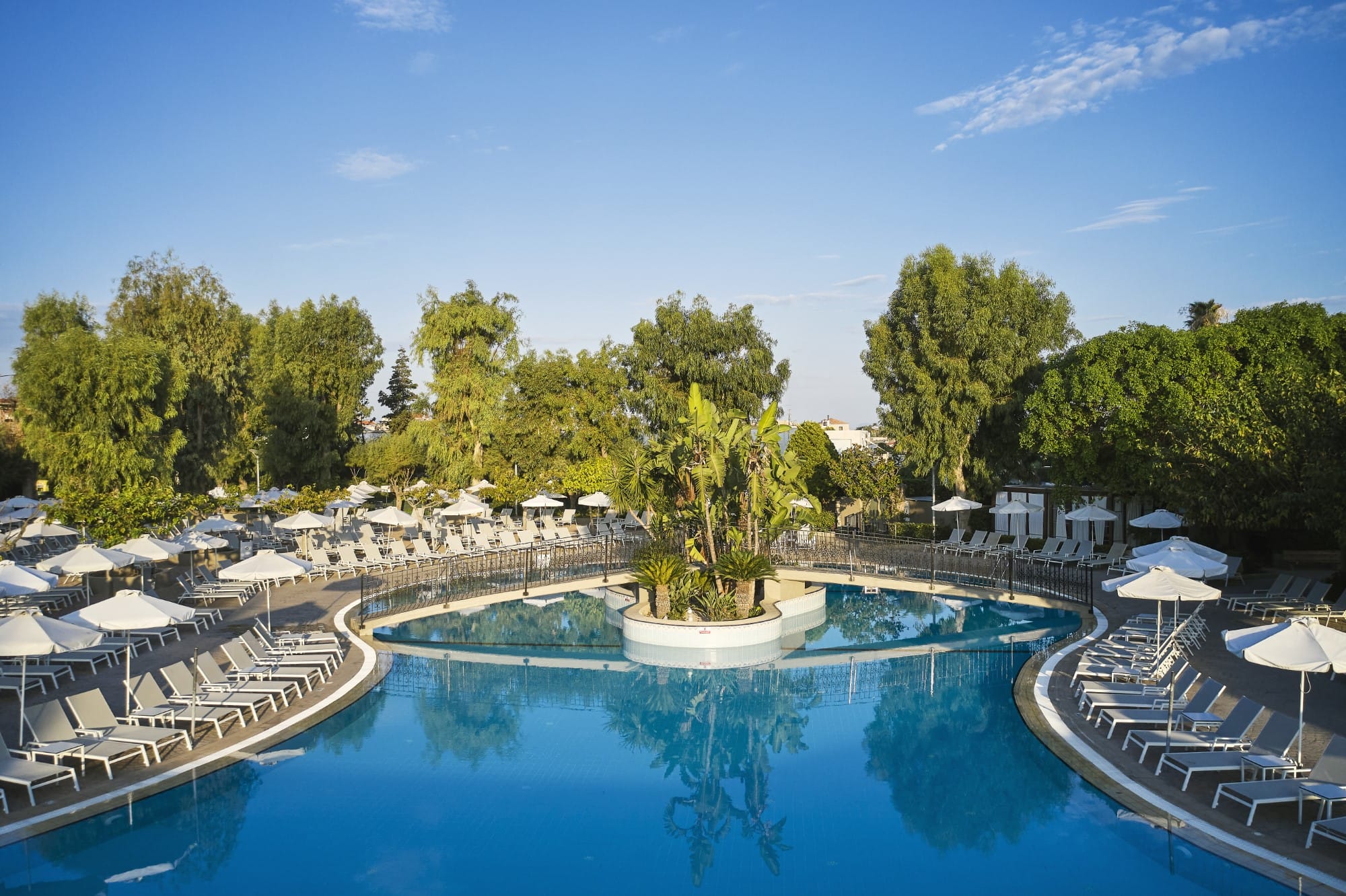 a pool with umbrellas and trees around it