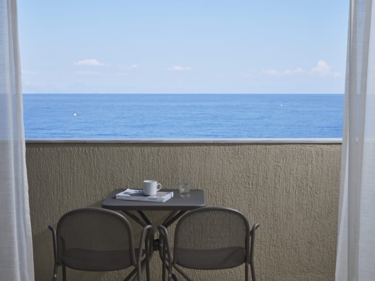 a table with a cup on it by a window with a view of the ocean