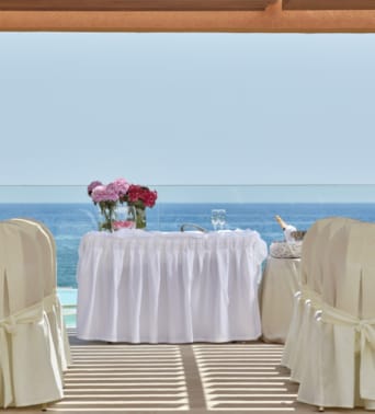 a table set with chairs and a view of the ocean