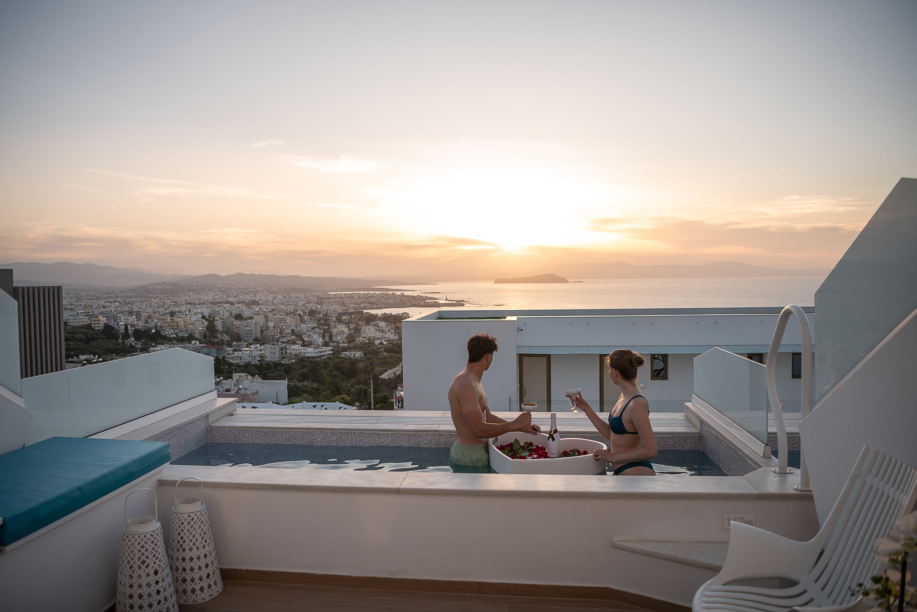 a man and woman sitting on a balcony overlooking a city