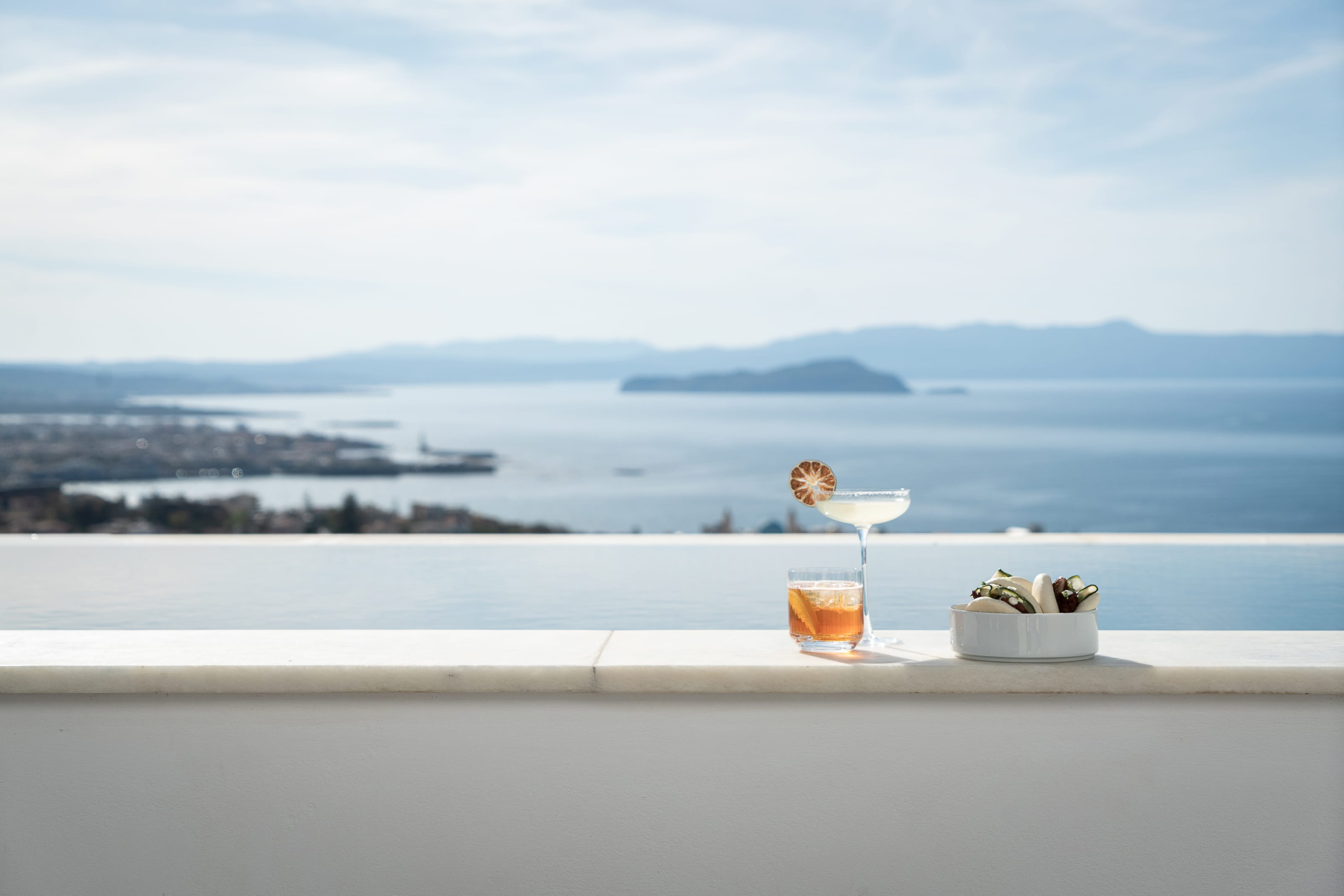 a person sitting at a table with a glass of liquid and a plate of food