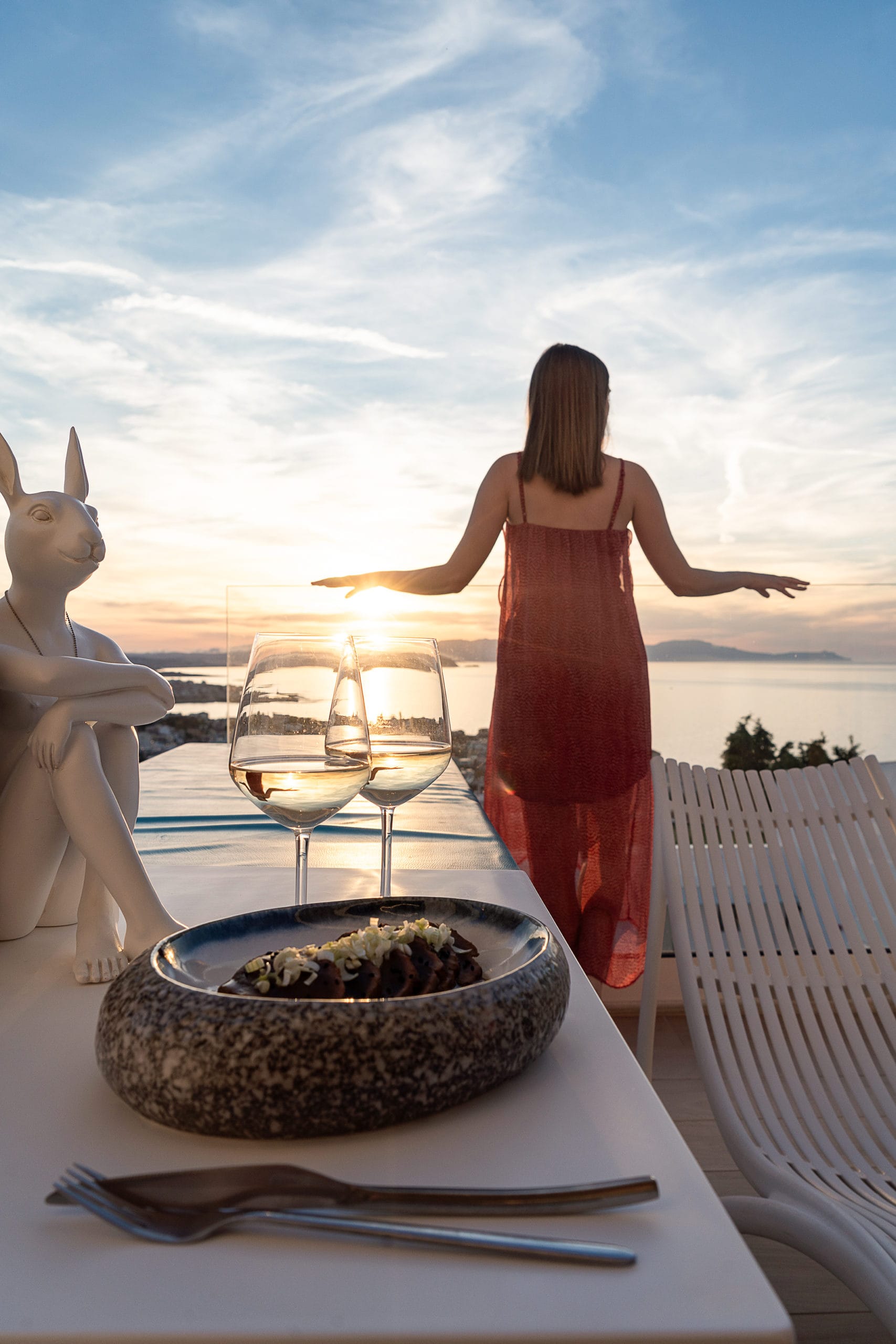 a person standing on a table with a plate of food and glasses