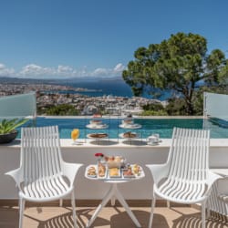 a deck with a table and chairs and a body of water in the background