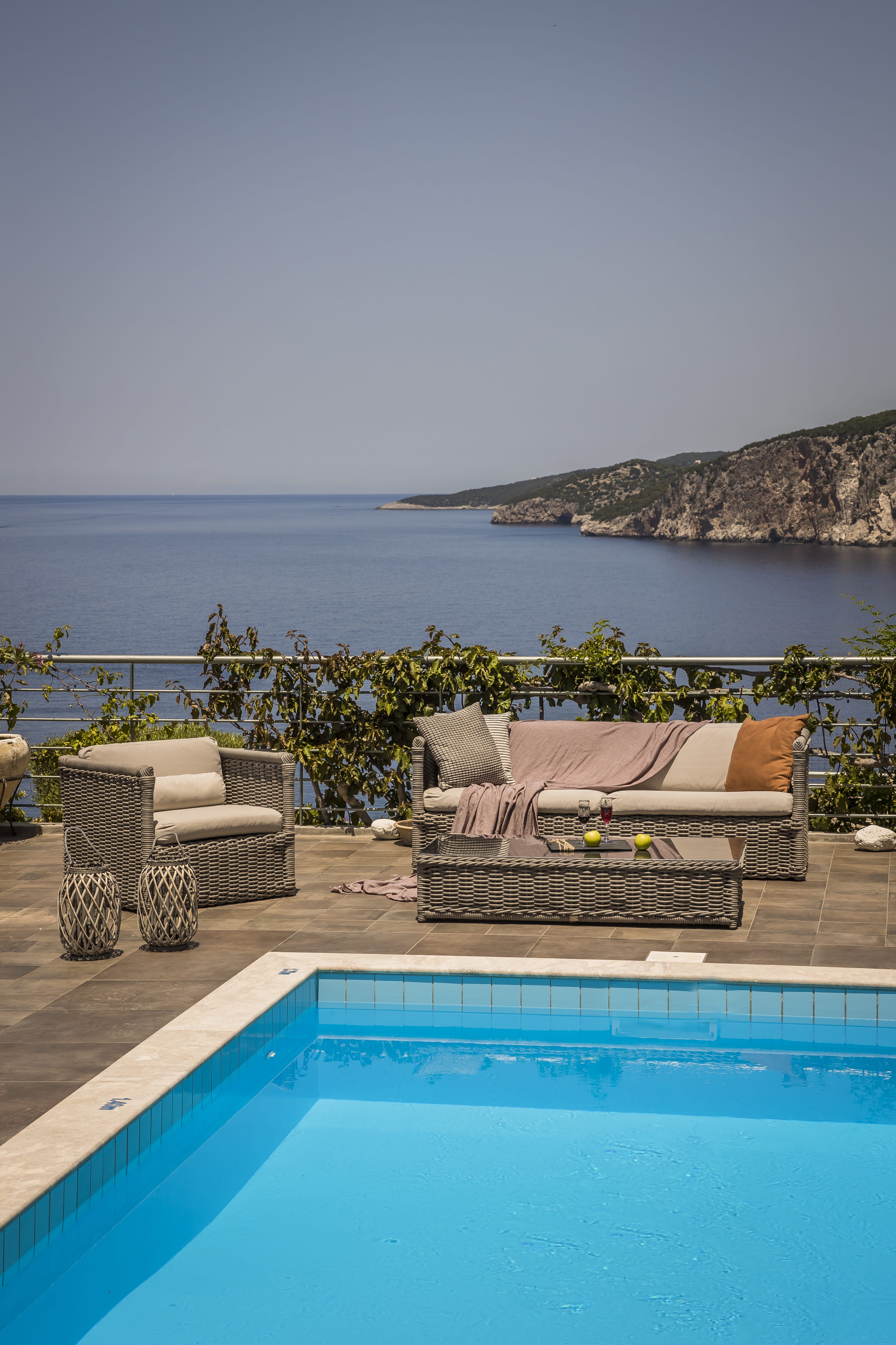 a pool with a couch and chairs by a body of water