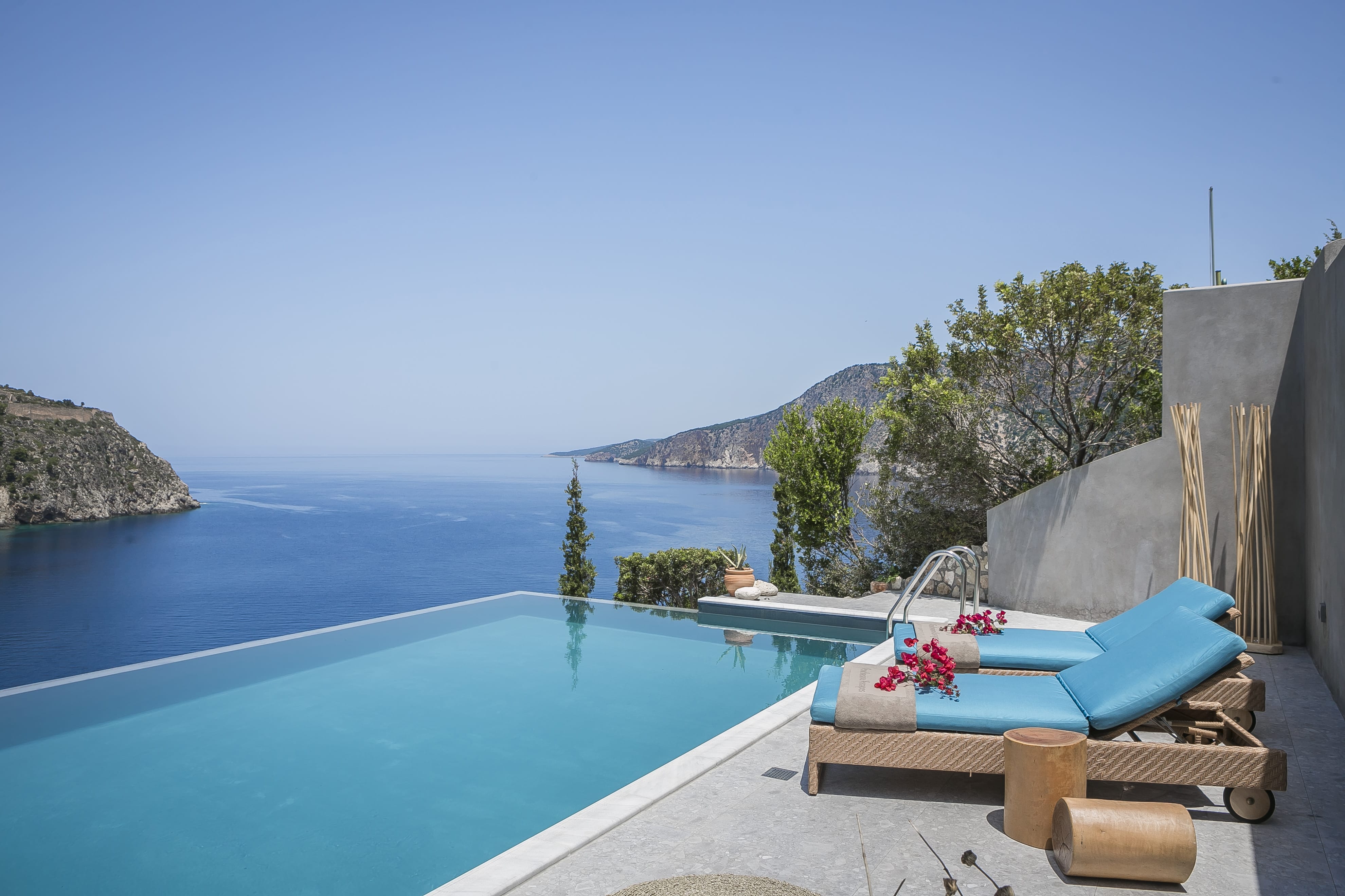 a pool with chairs and a deck overlooking a beach