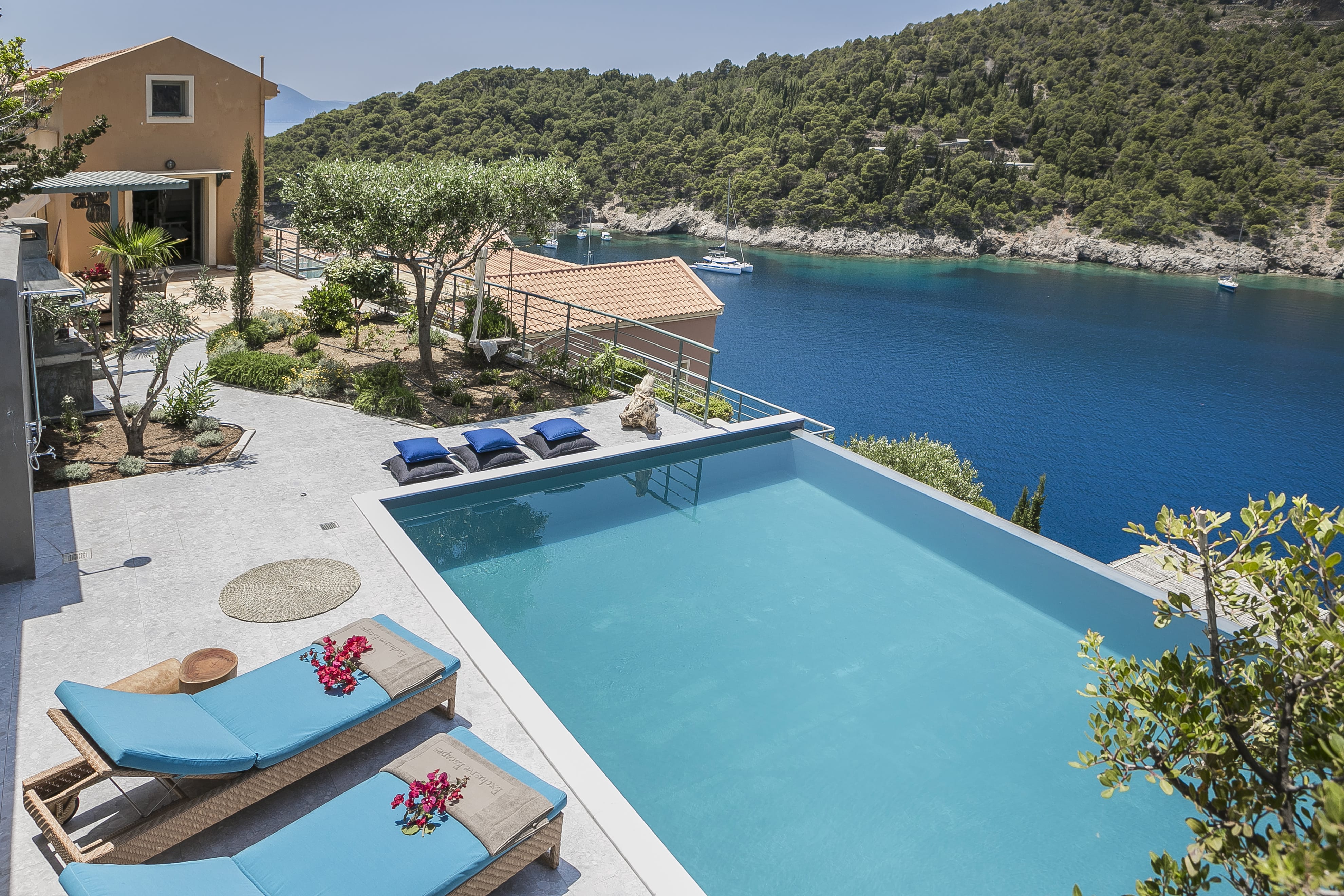 a swimming pool with chairs and a deck with trees and a building in the background