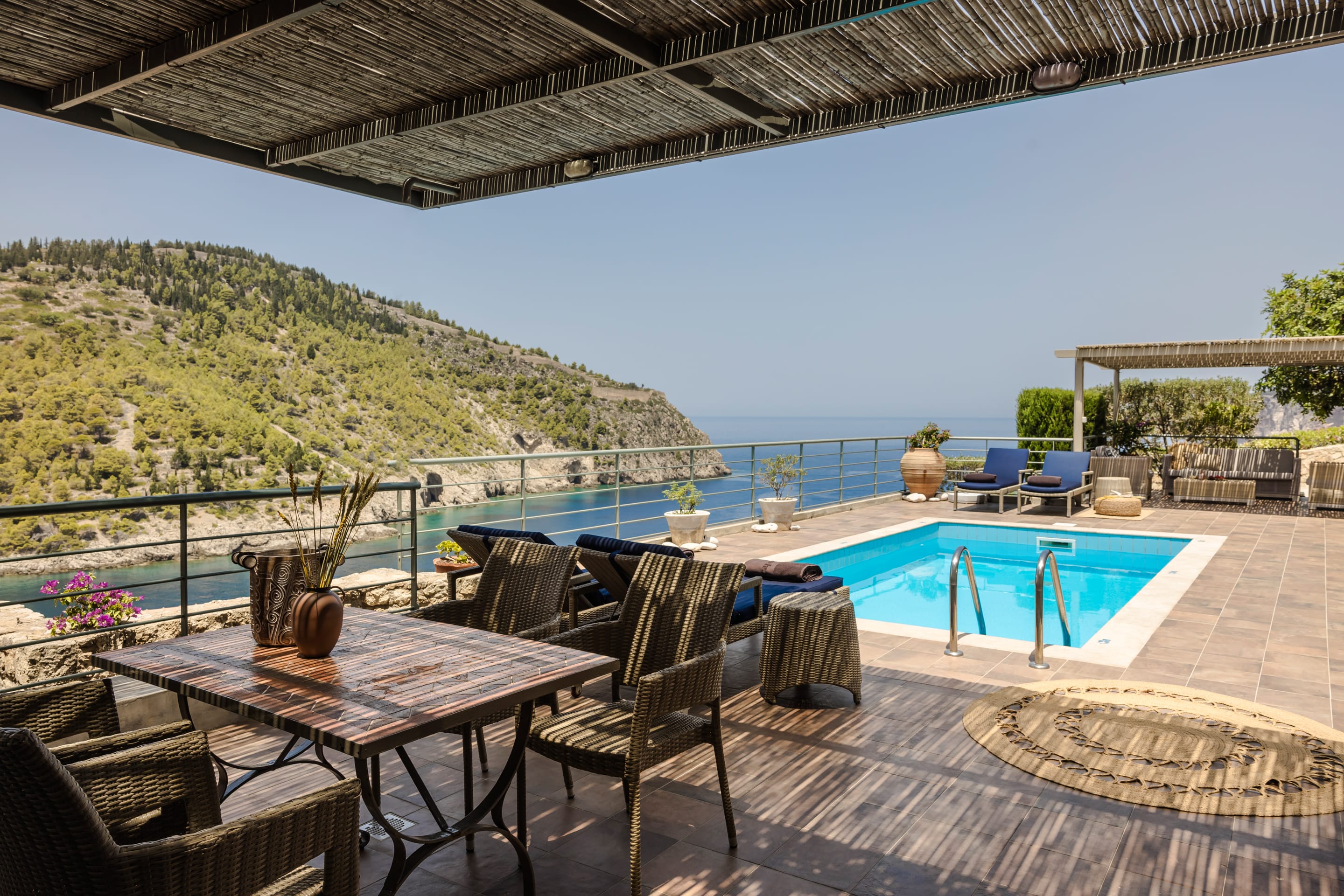a pool with chairs and a table by it with a hill in the background