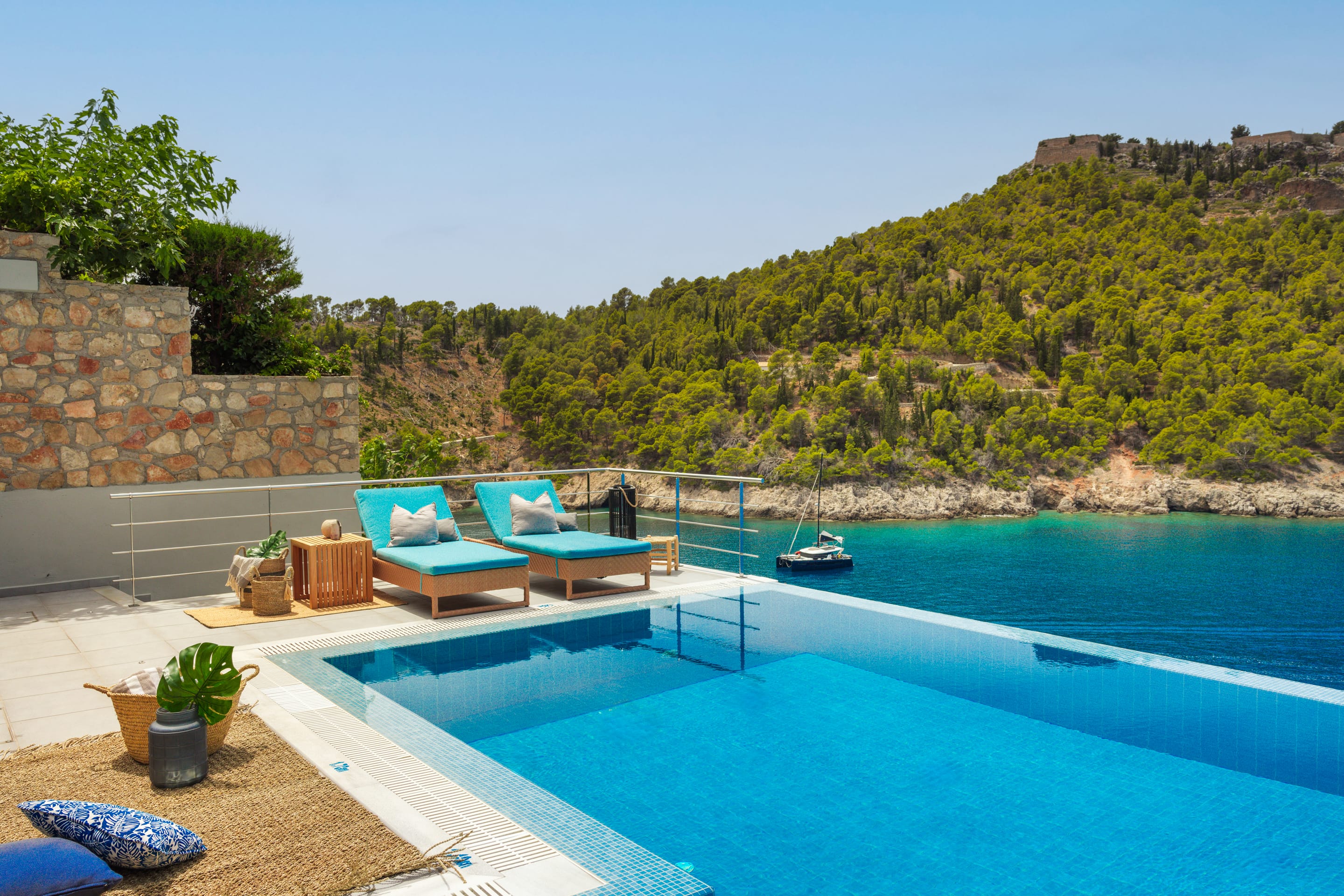 a pool with lounge chairs and a boat in the background