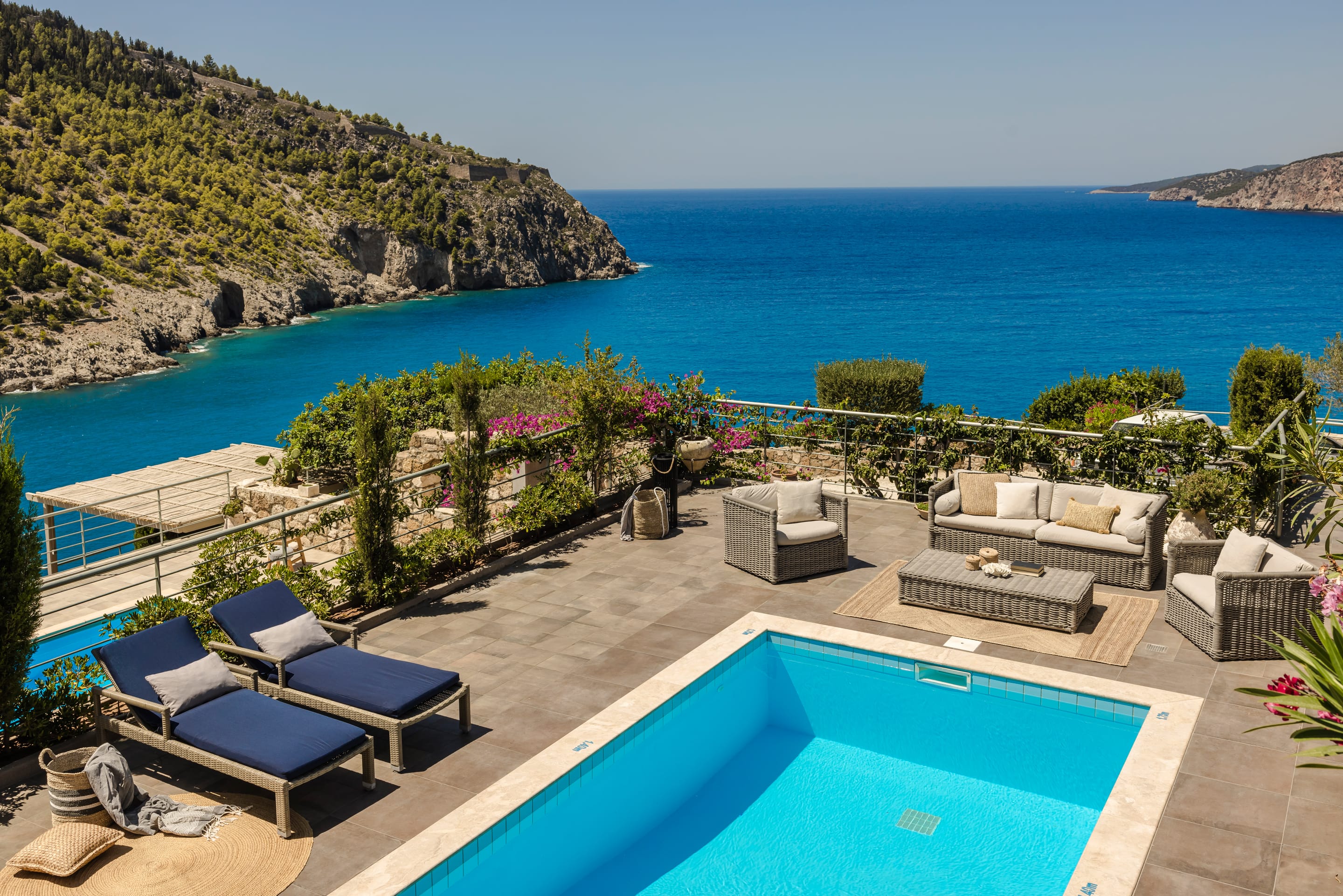a pool with lounge chairs and a beach in the background