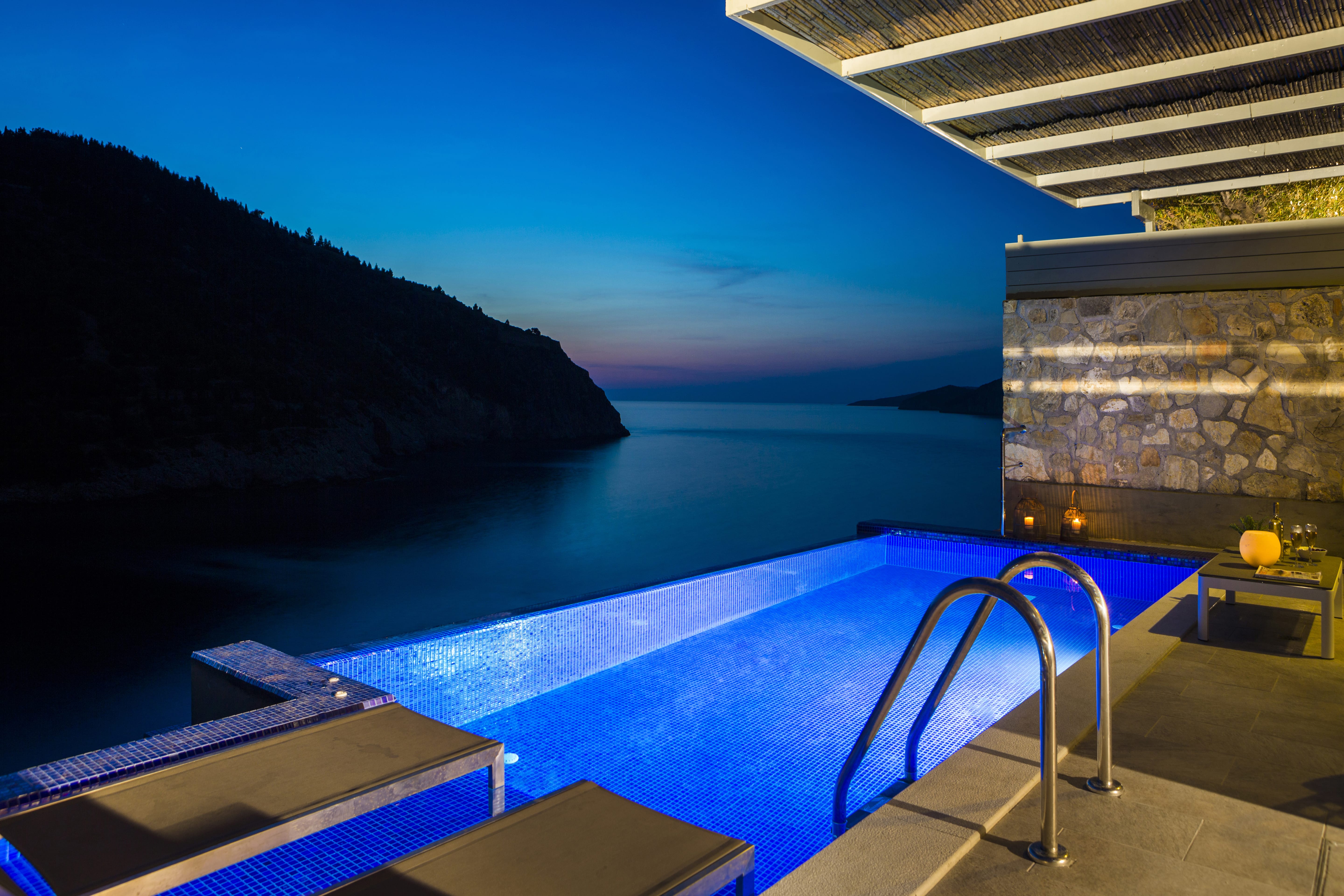 a pool with a stone wall and a stone building with a blue sky
