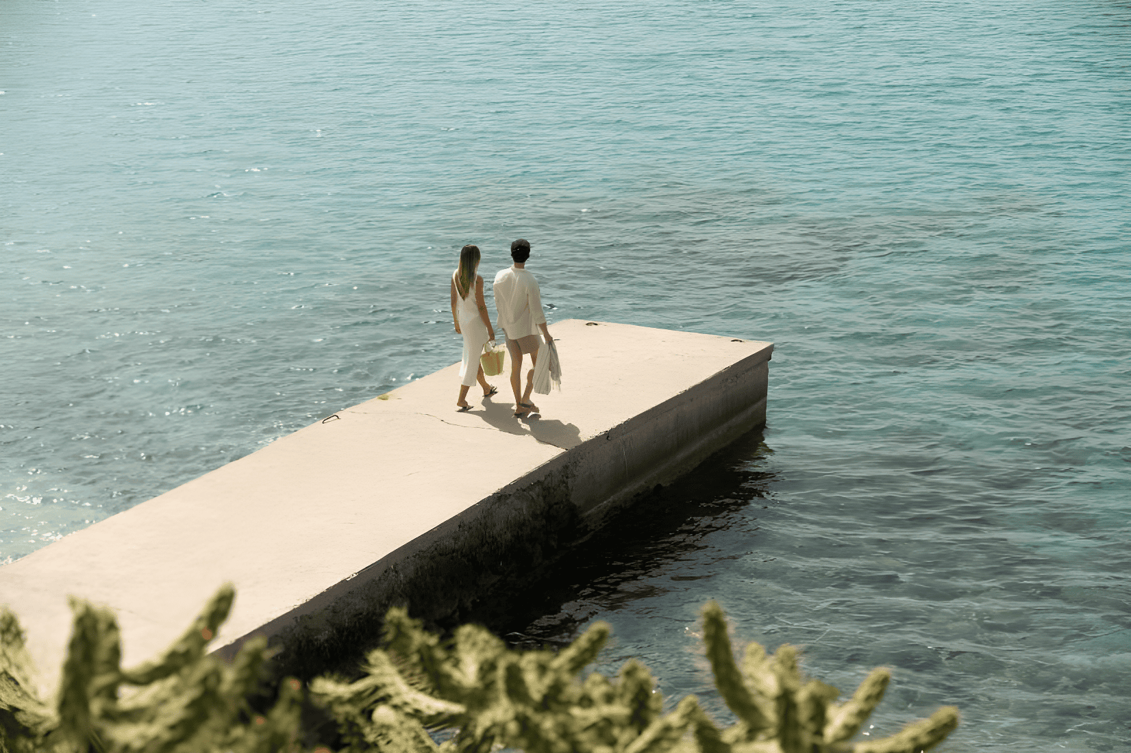 a man and woman walking on a dock over water