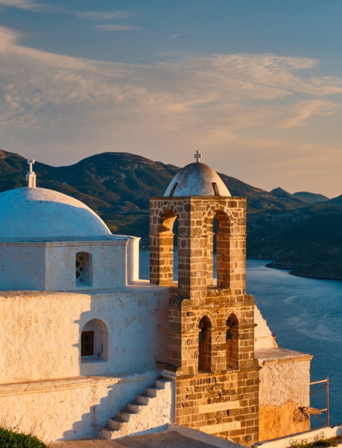 a building with a tower and a body of water in the background