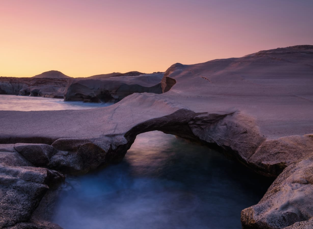 a body of water with rocks and mountains in the background