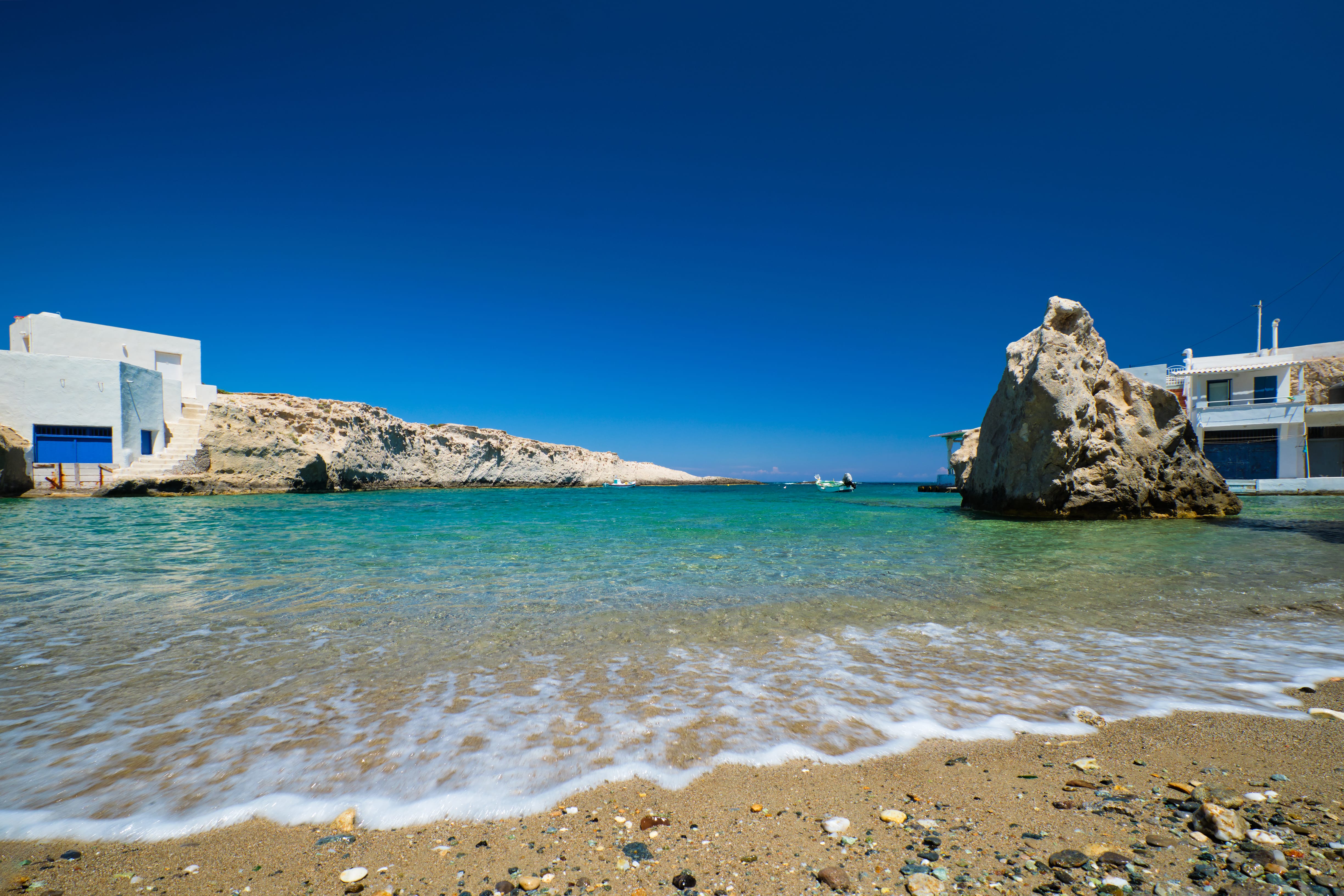 a beach with a building and a rock in the water