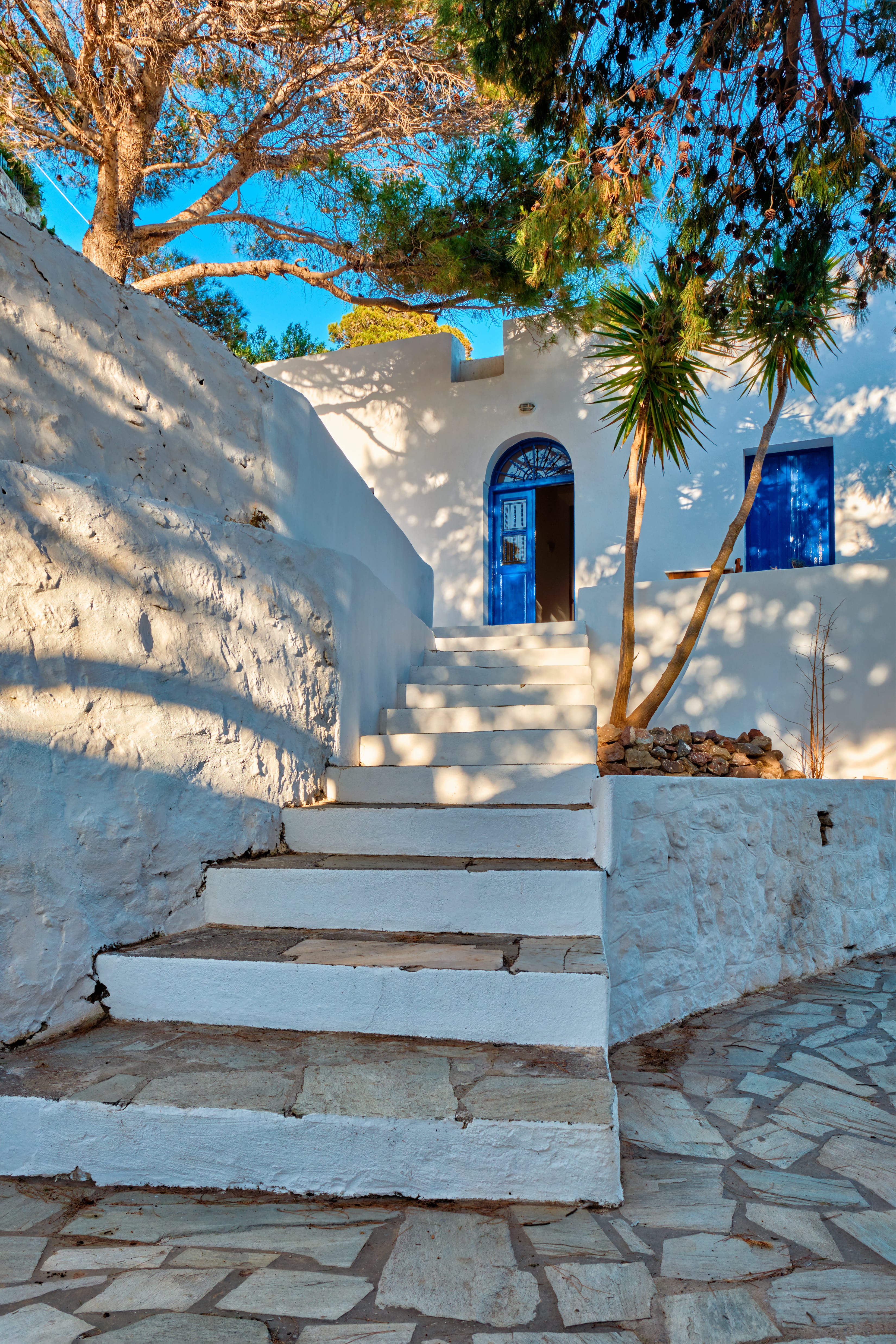 a stone staircase leading up to a building with trees and blue sky