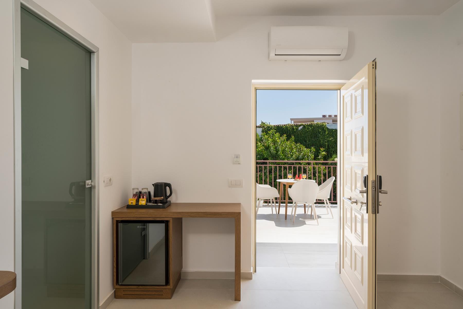 a room with a desk and a door with a view of the ocean