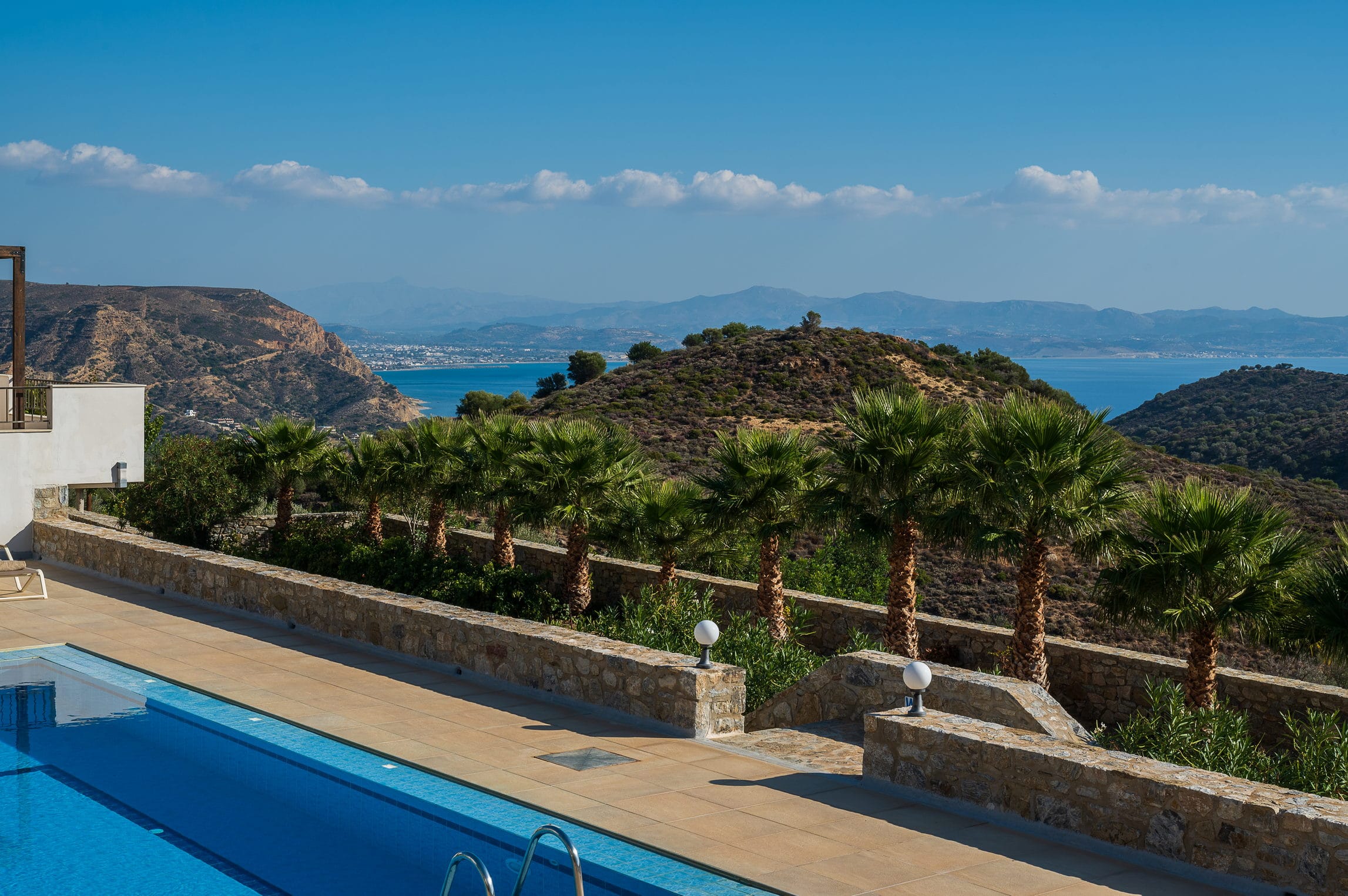 a pool next to a hill with trees and a body of water
