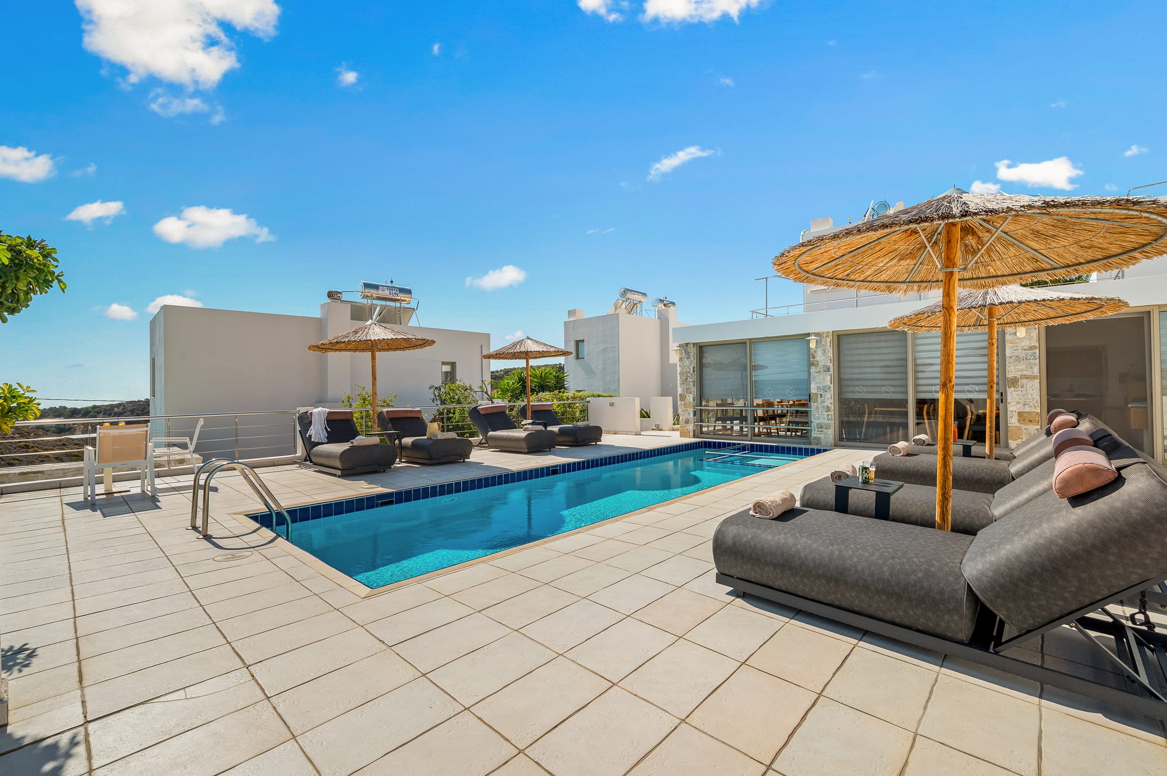 a pool and lounge chairs on a patio with a view of the city