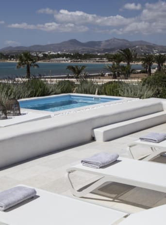 a pool with lounge chairs and a deck with a view of the ocean