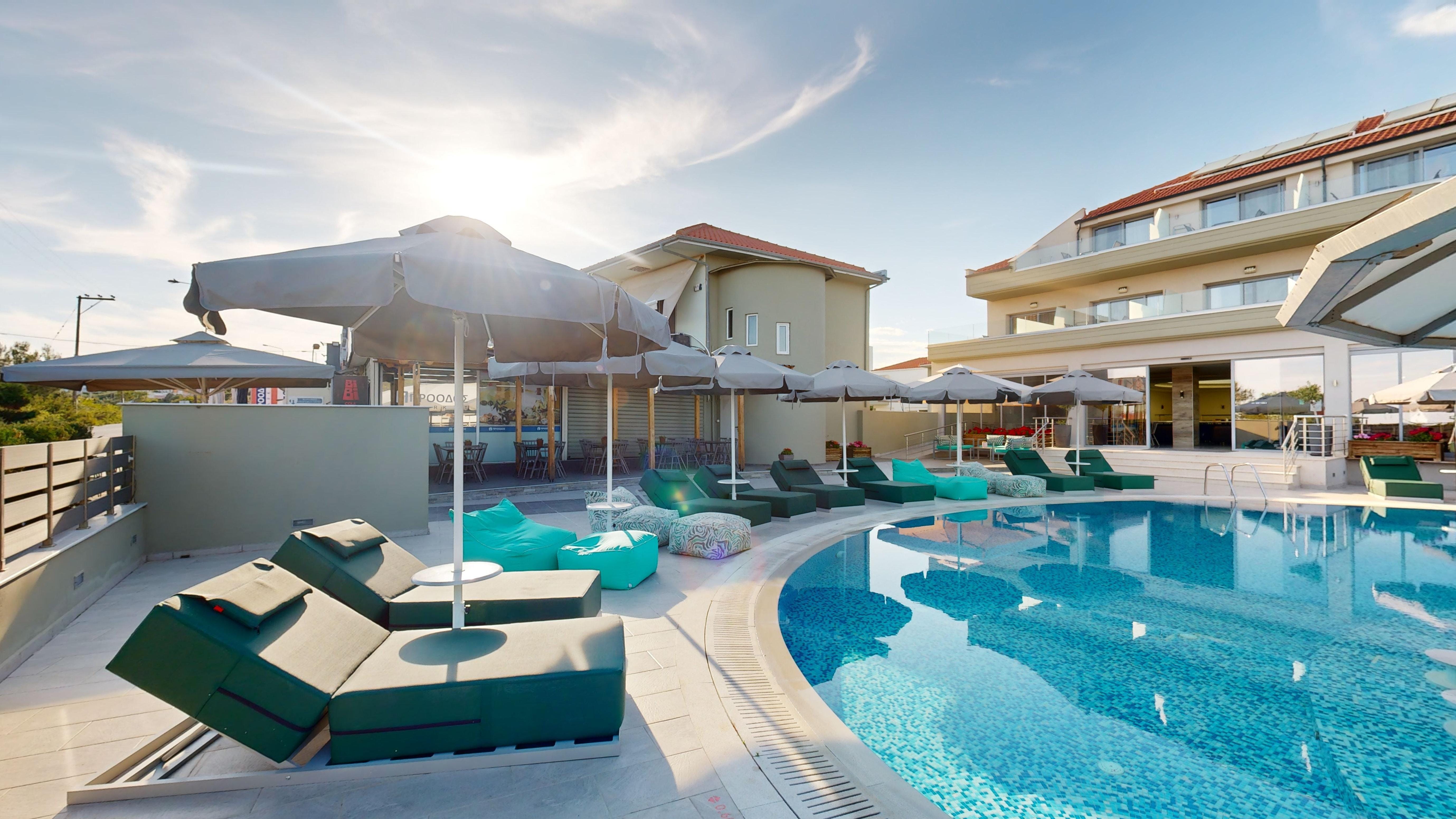 a pool with lounge chairs and umbrellas by a building